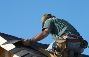 Man on a roof replacing shingles